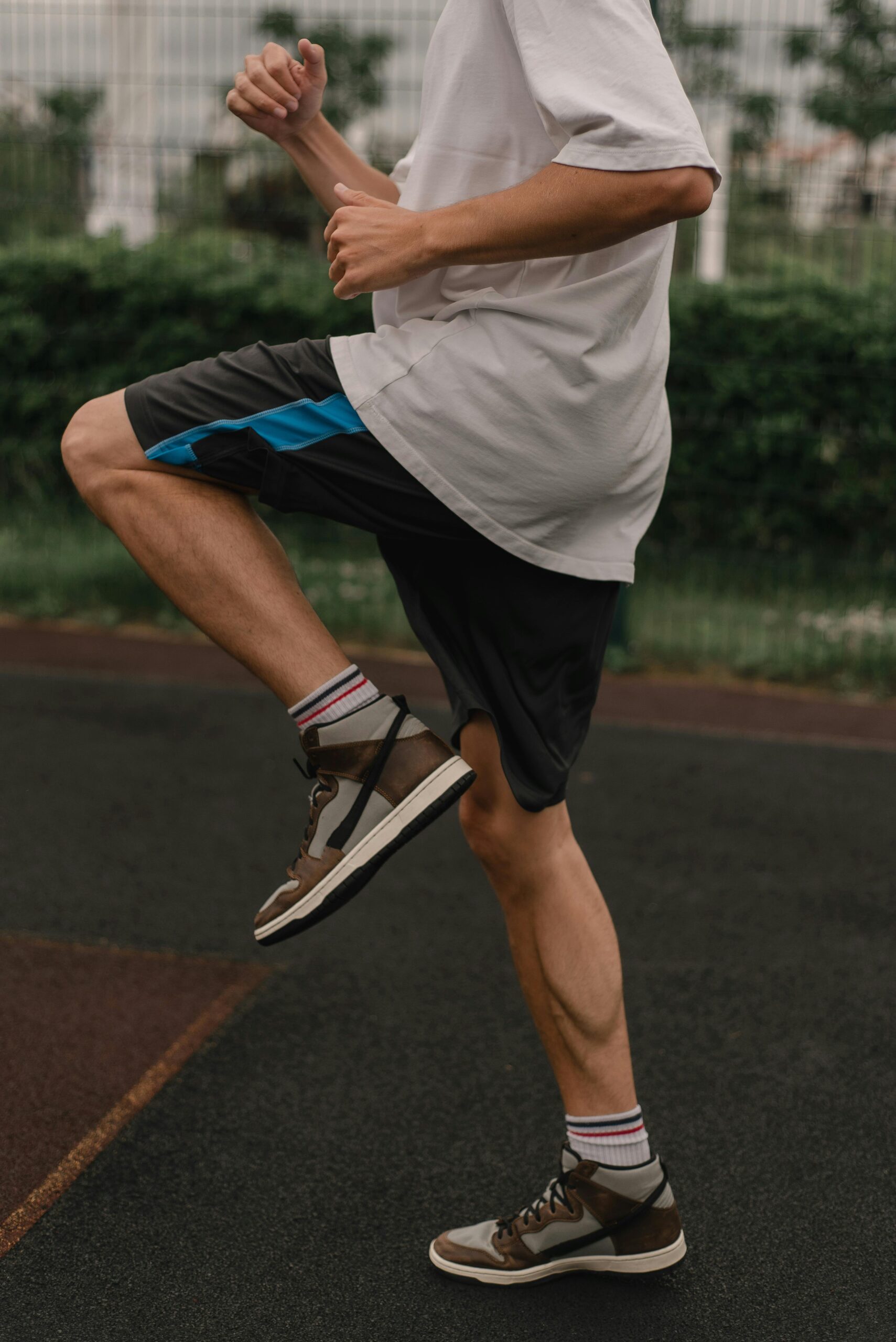 Man performing a leg raise exercise on outdoor track in summer.